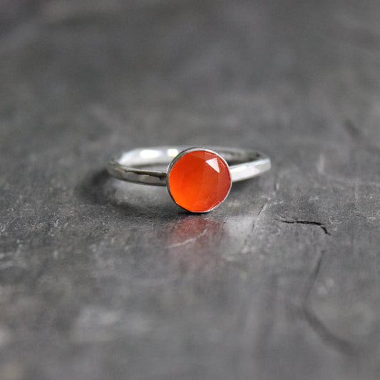 Silver ring with a red stone on a dark textured surface