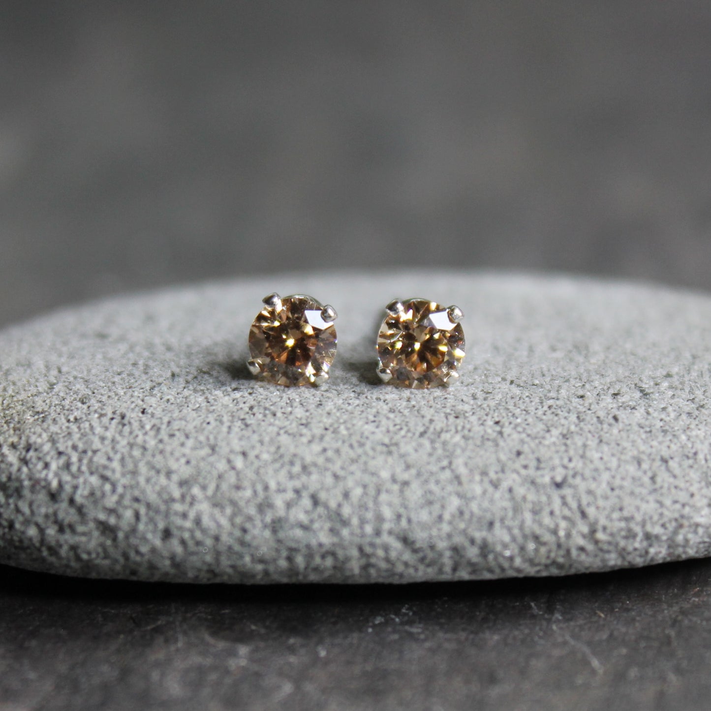 These stud earrings have 4mm round faceted champagne colored cubic zirconia (CZ) gemstones set in 4-prong sterling silver earring settings and earring backs.