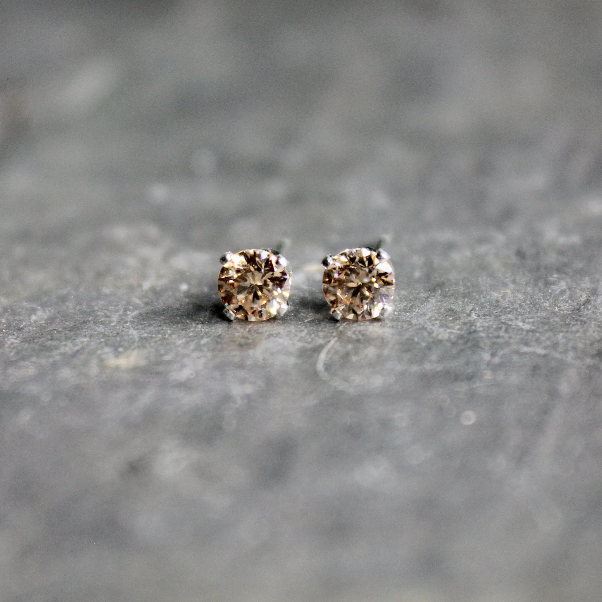 These stud earrings have 4mm round faceted champagne colored cubic zirconia (CZ) gemstones set in 4-prong sterling silver earring settings and earring backs.