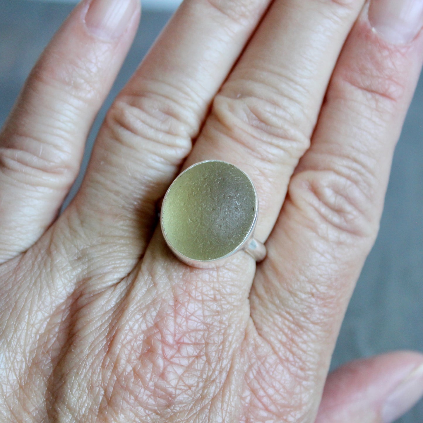 Close-up of a hand wearing a Champagne Sea glass ring with a silver band.