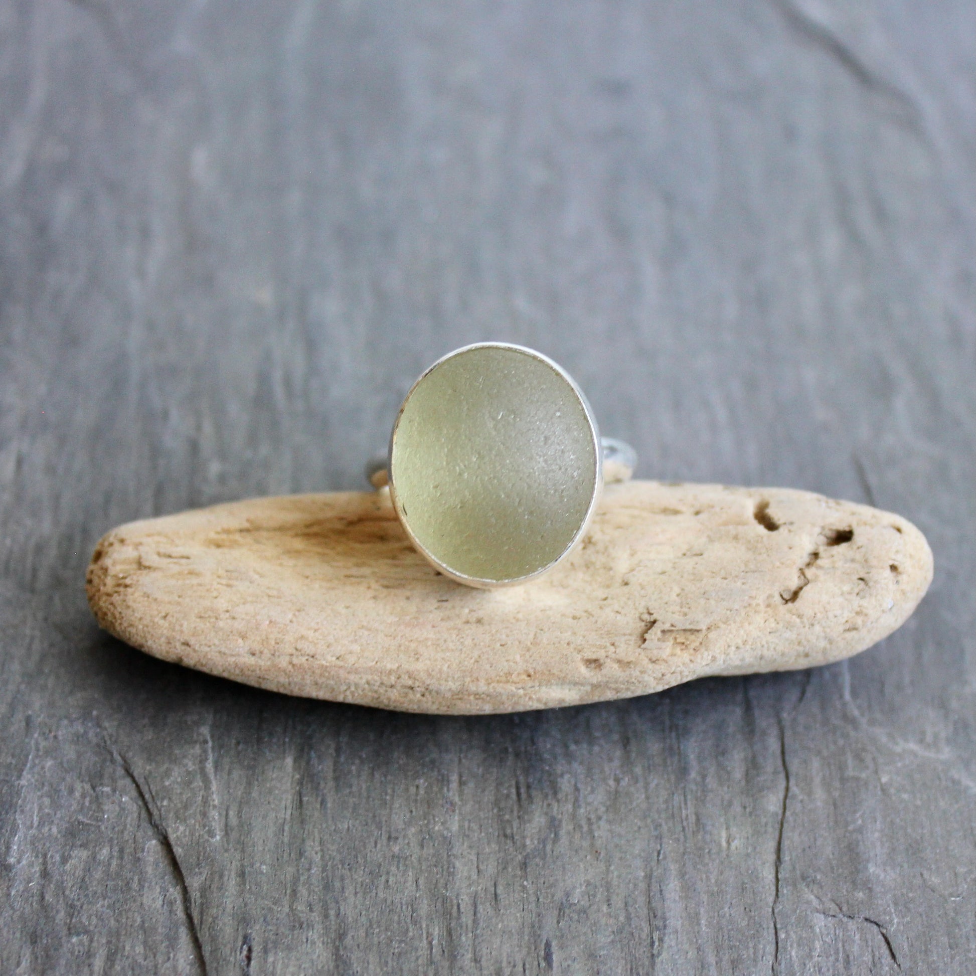 Champagne Sea Glass ring on a piece of driftwood with a gray background