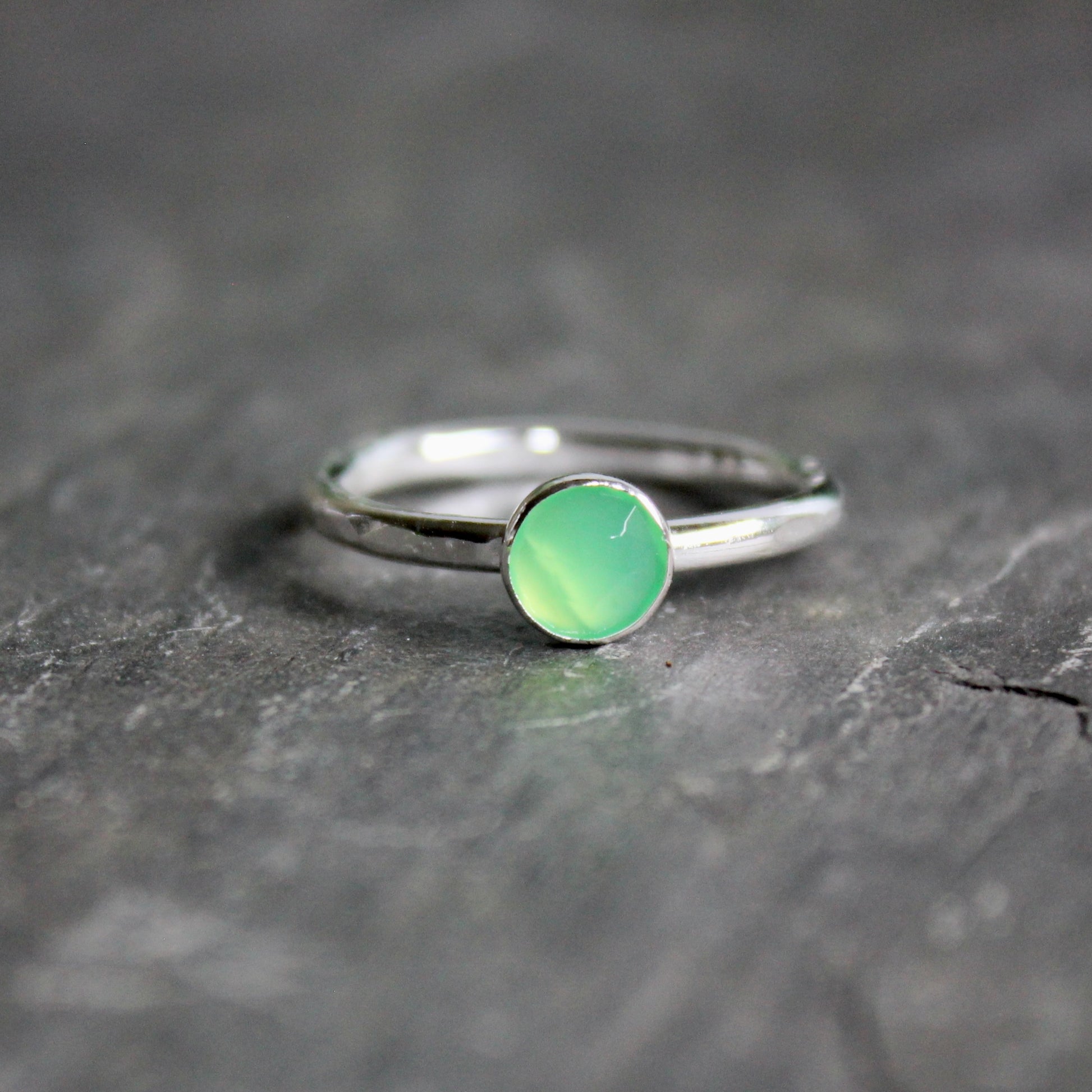Silver ring with a green chrysoprase gemstone on a dark surface