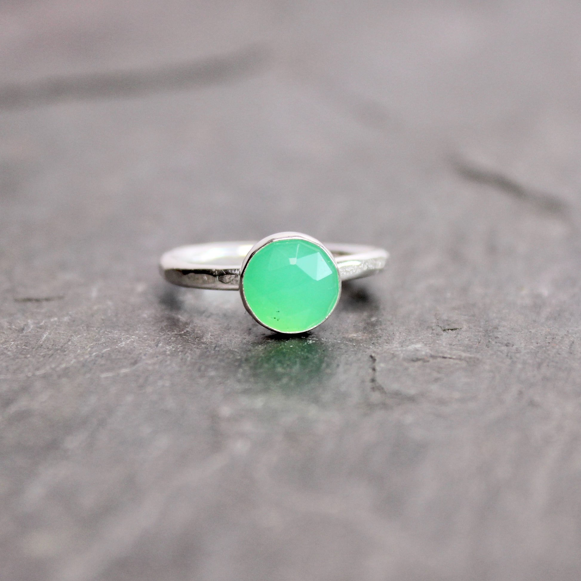 Silver ring with a green chrysoprase gemstone on a dark surface