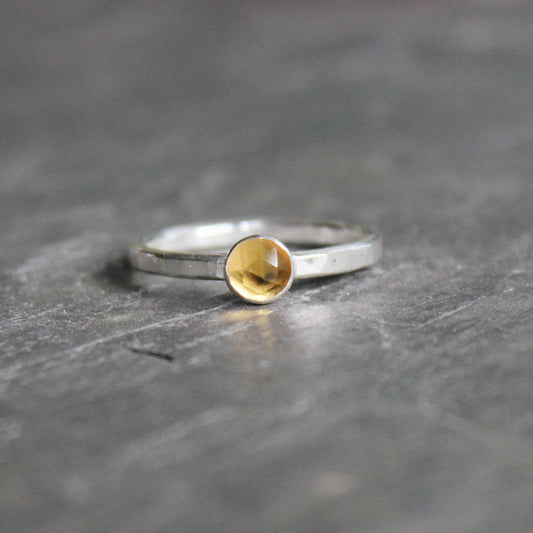 Silver ring with a gold accent on a dark stone surface