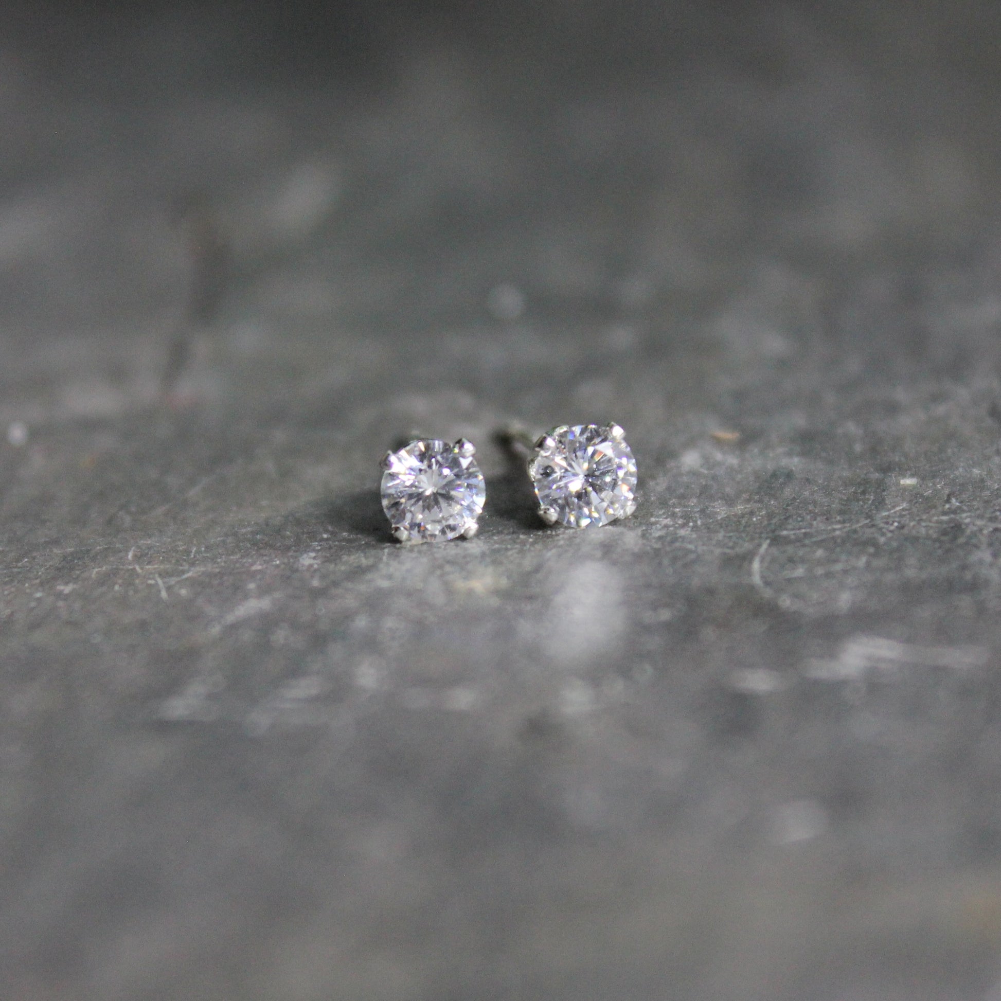 These stud earrings have 4mm round faceted cubic zirconia gemstones set in sterling silver 4-prong earring settings with earring backs.