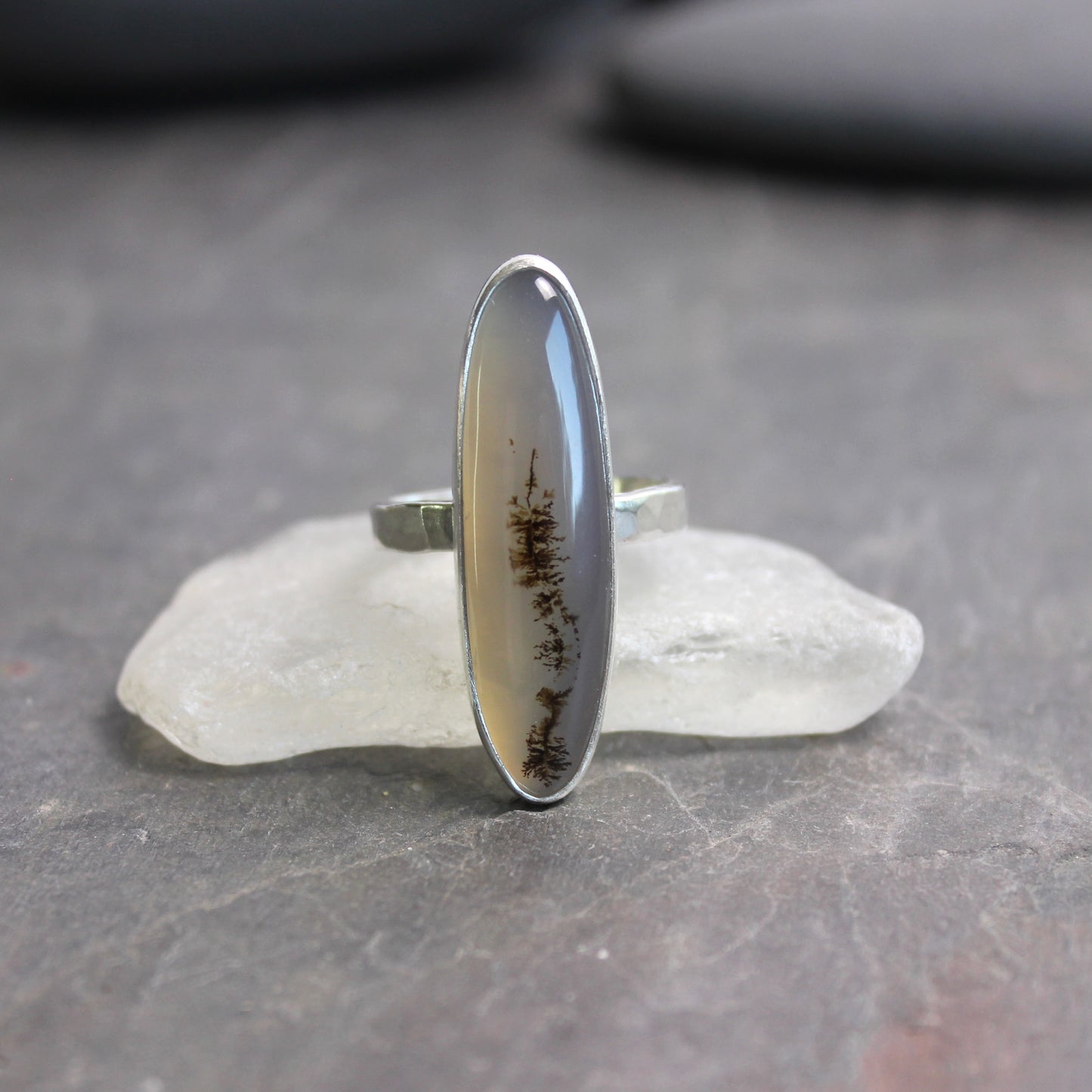 Silver ring with a natural stone inlay on a gray surface