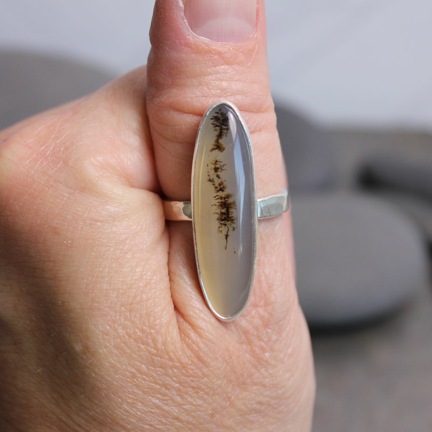 Hand wearing a ring with an oval stone and silver band