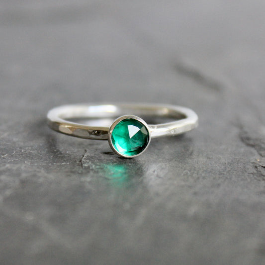 Silver ring with a green gemstone on a gray surface