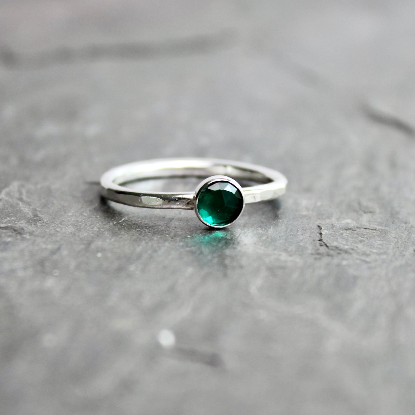 Silver ring with a green gemstone on a gray surface