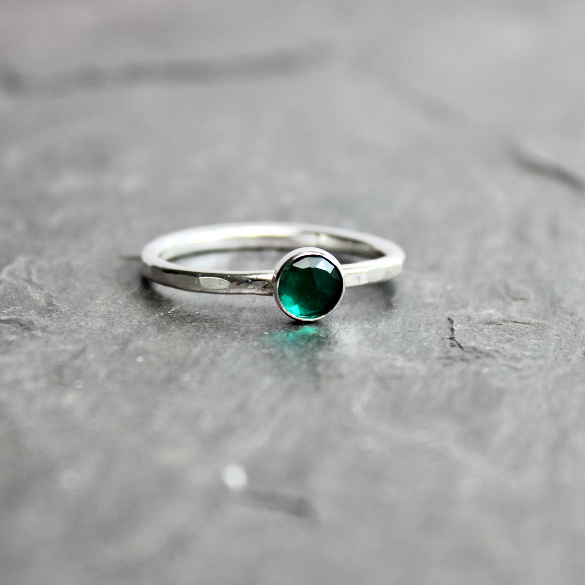 Silver ring with a green gemstone on a gray surface