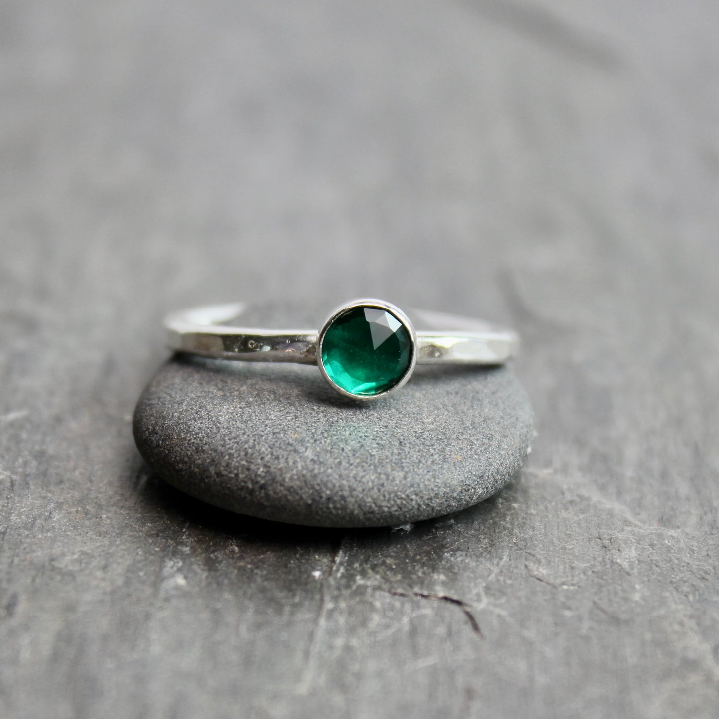Silver ring with a green gemstone on a gray stone surface