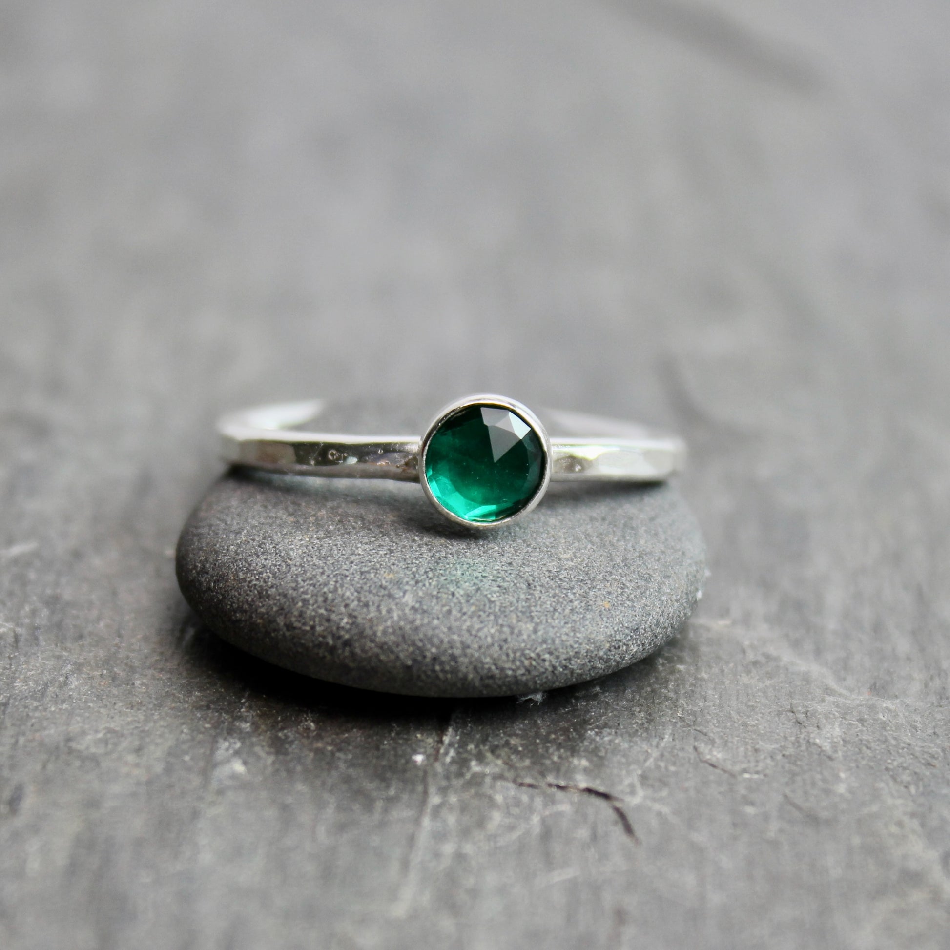 Silver ring with a green gemstone on a gray stone surface
