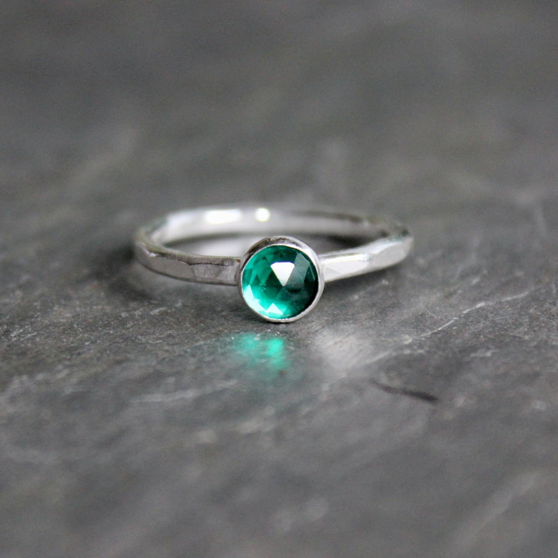 Silver ring with a green gemstone on a gray surface