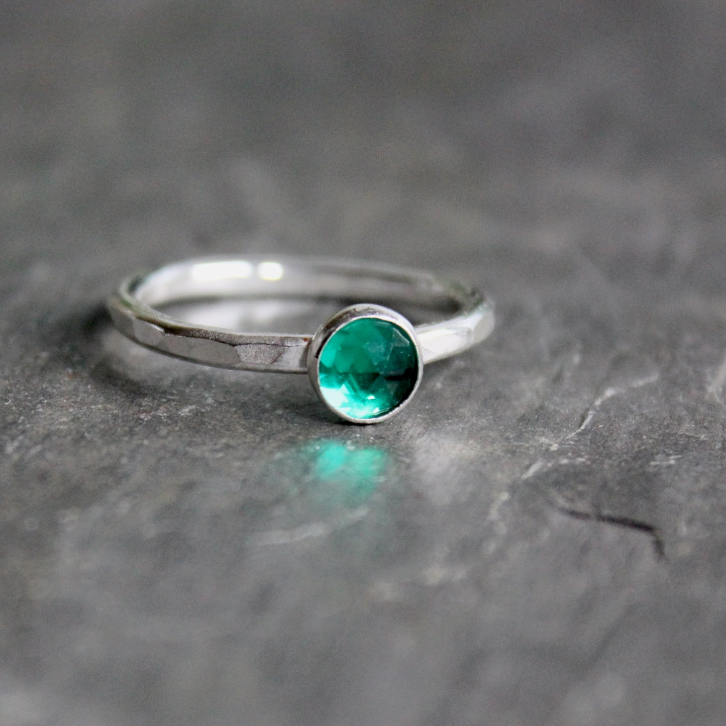 Silver ring with a green gemstone on a gray surface
