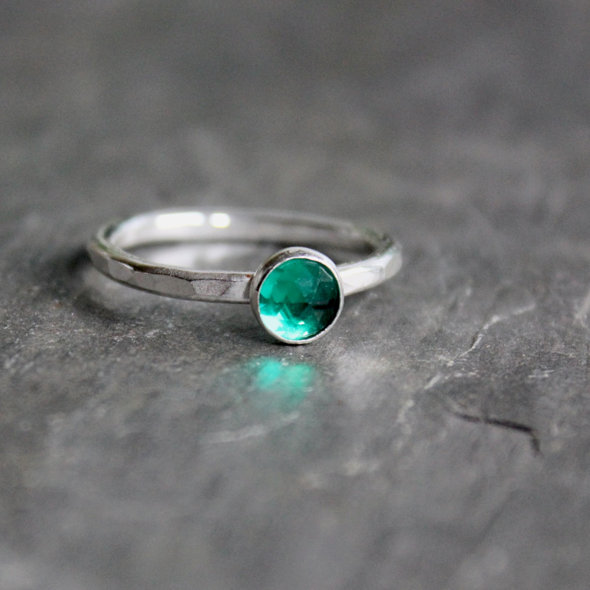 Silver ring with a green gemstone on a gray surface