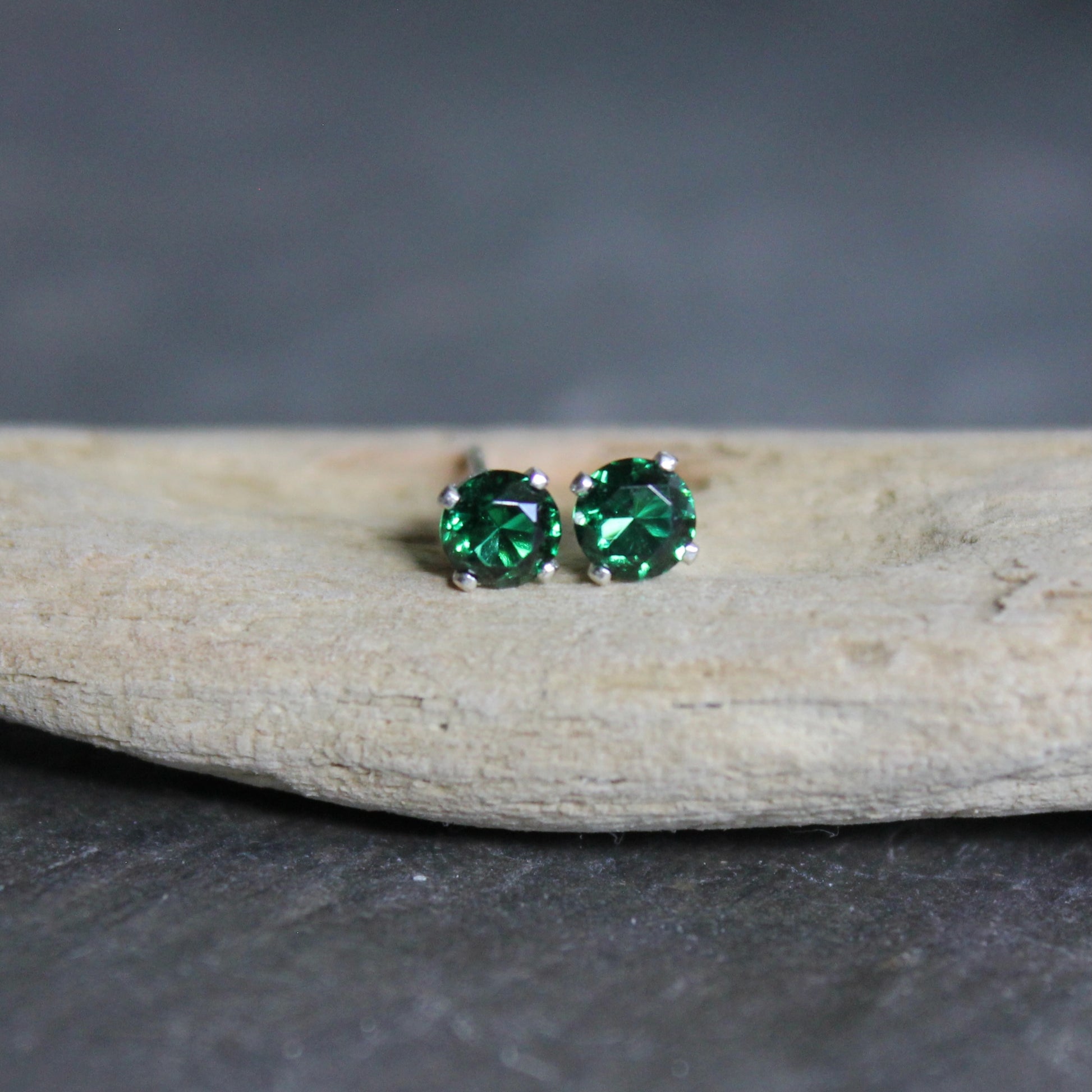 These stud earrings have 4mm round faceted lab created emeralds set in sterling silver 4-prong stud earring settings with earring backs. 