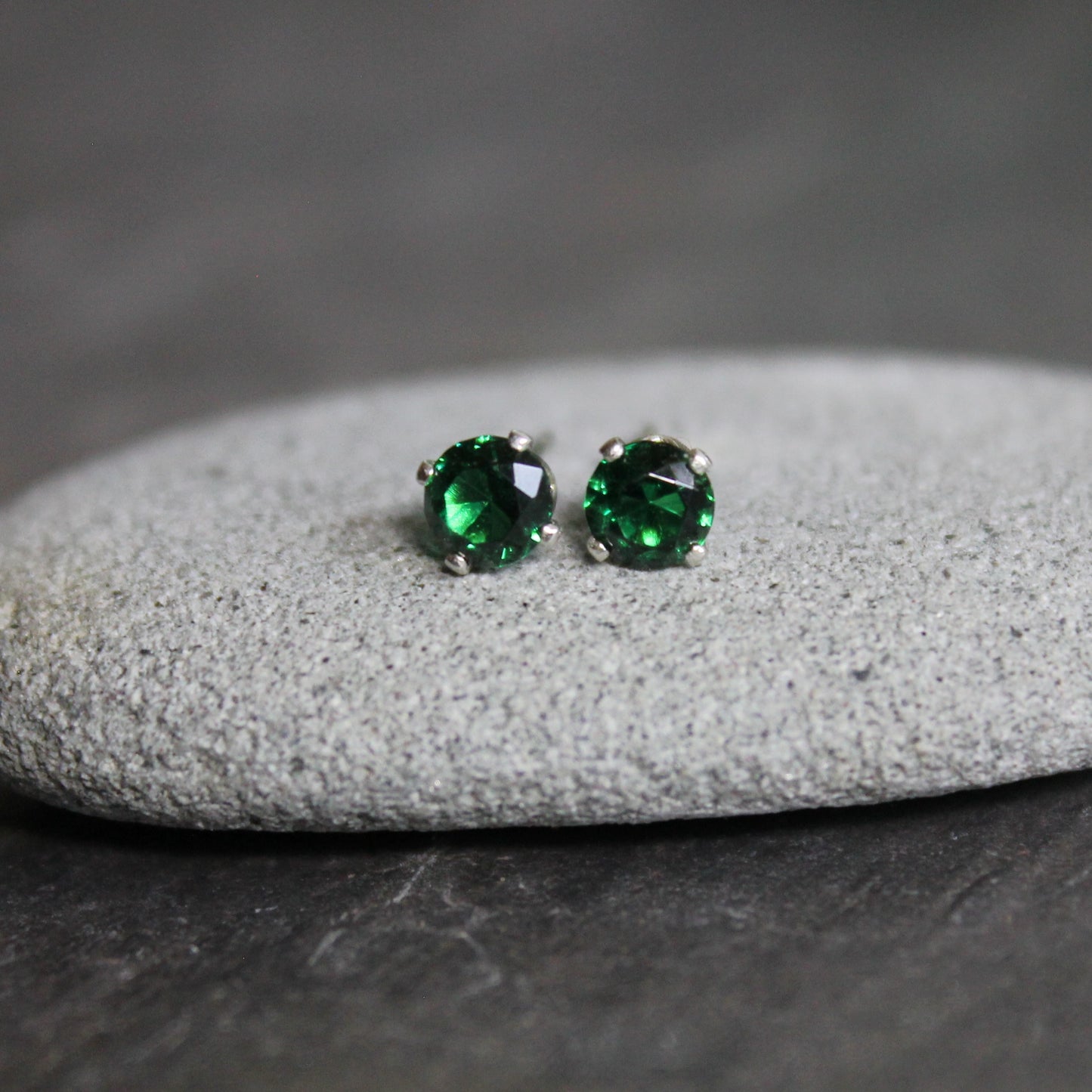 These stud earrings have 4mm round faceted lab created emeralds set in sterling silver 4-prong stud earring settings with earring backs. 