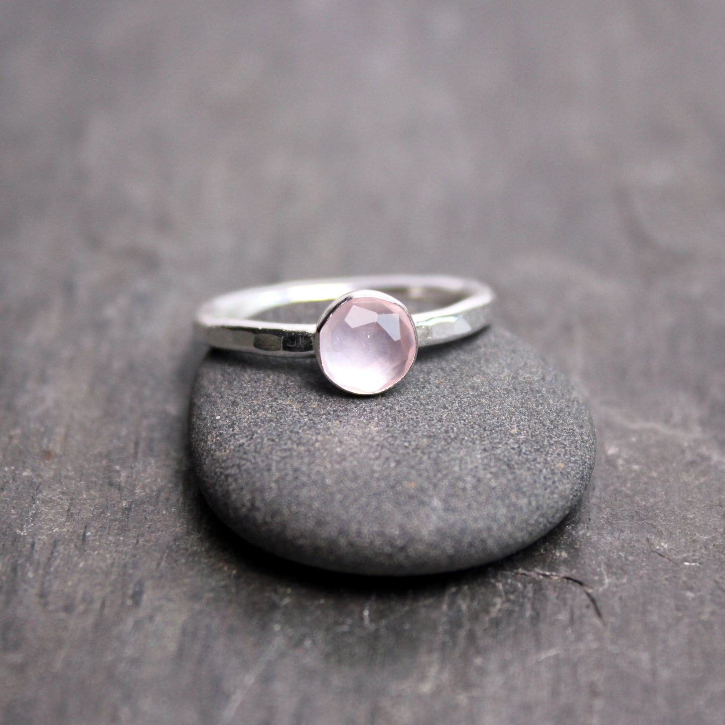 Silver ring with a pink gemstone on a gray stone surface