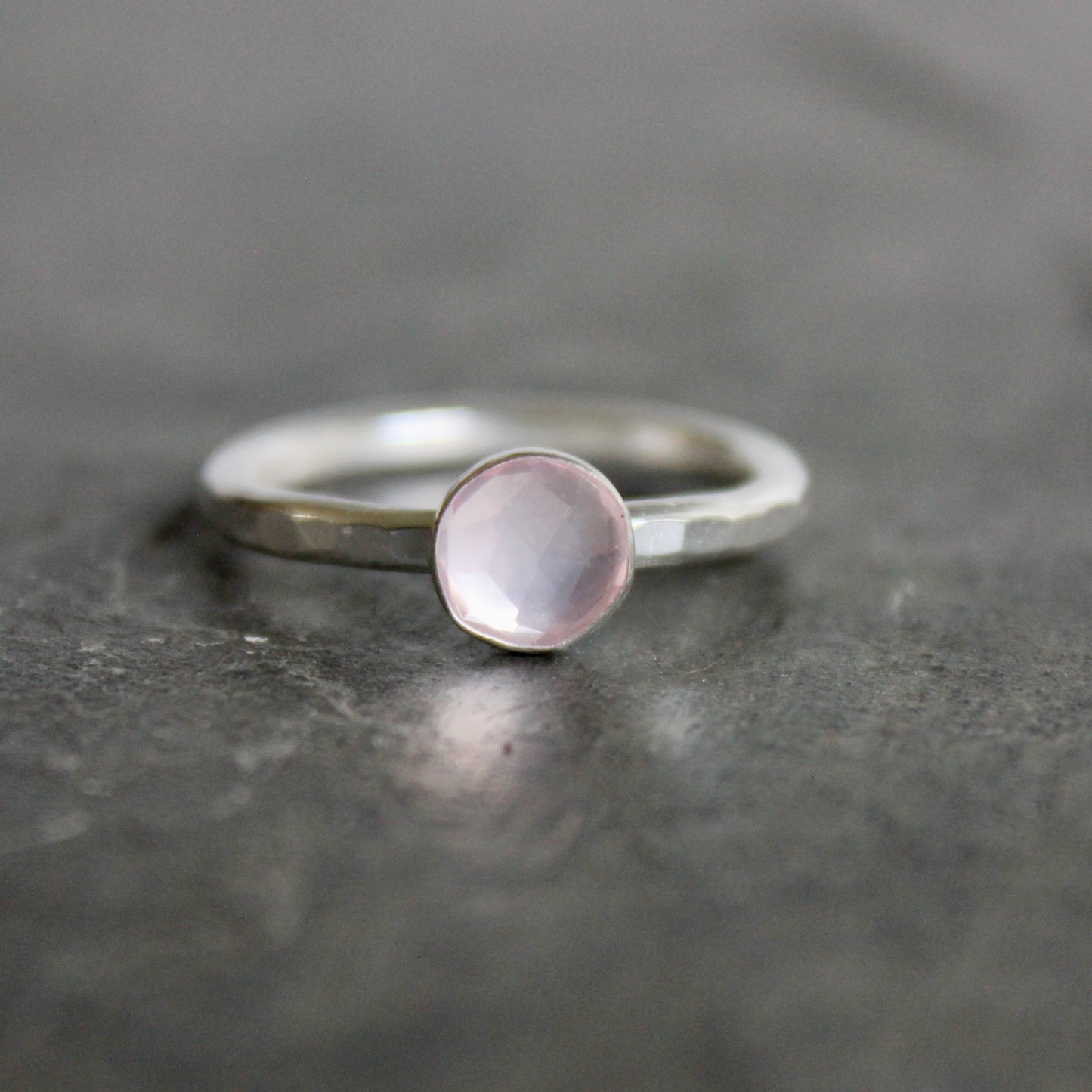 Silver ring with a pink gemstone on a dark gray surface