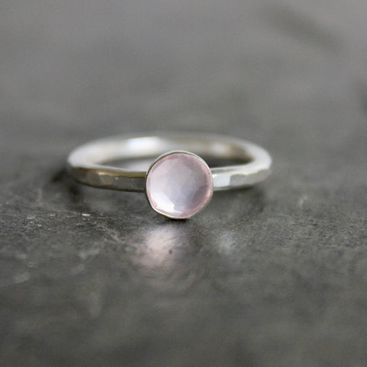 Silver ring with a pink gemstone on a dark gray surface