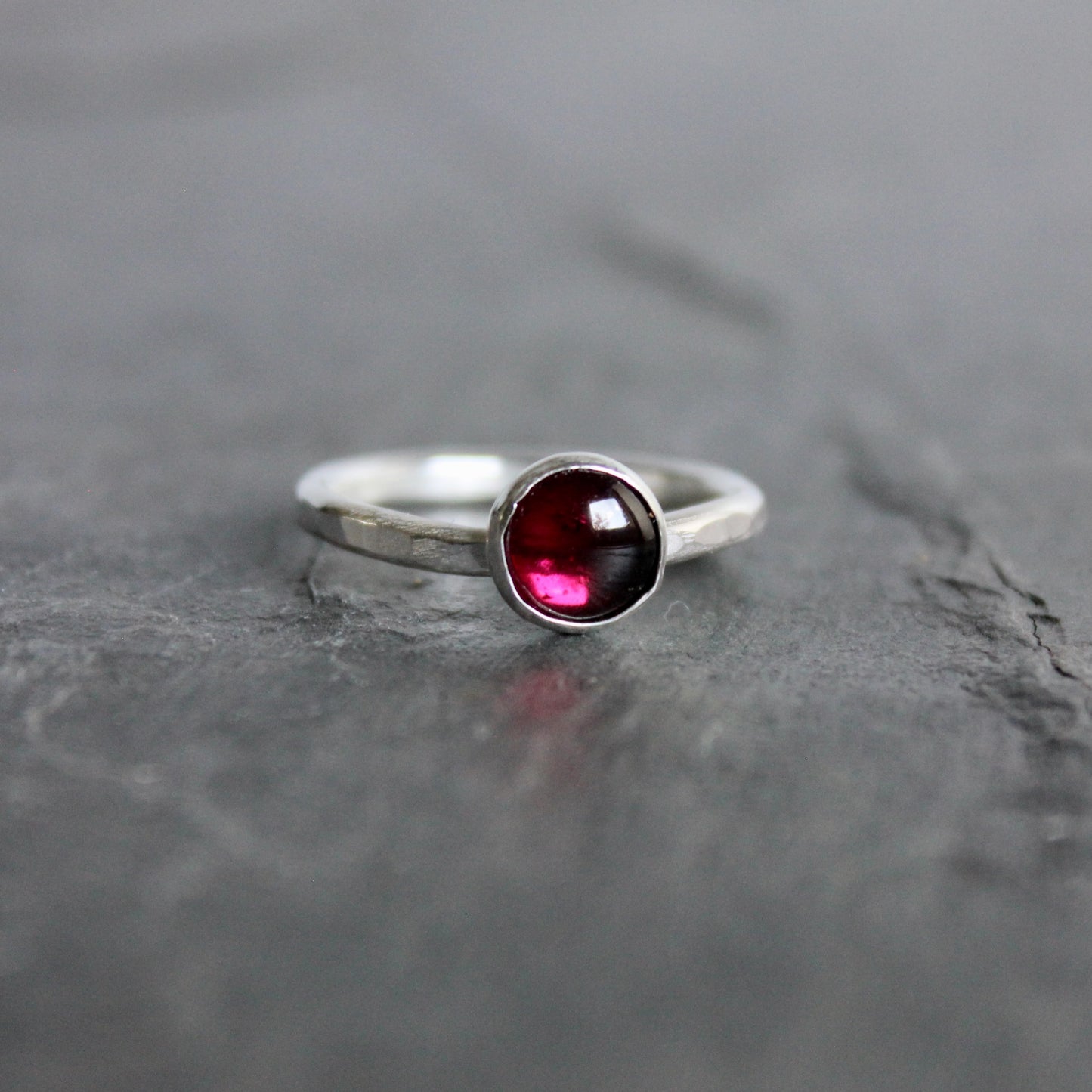 Silver ring with a red gemstone on a gray stone surface