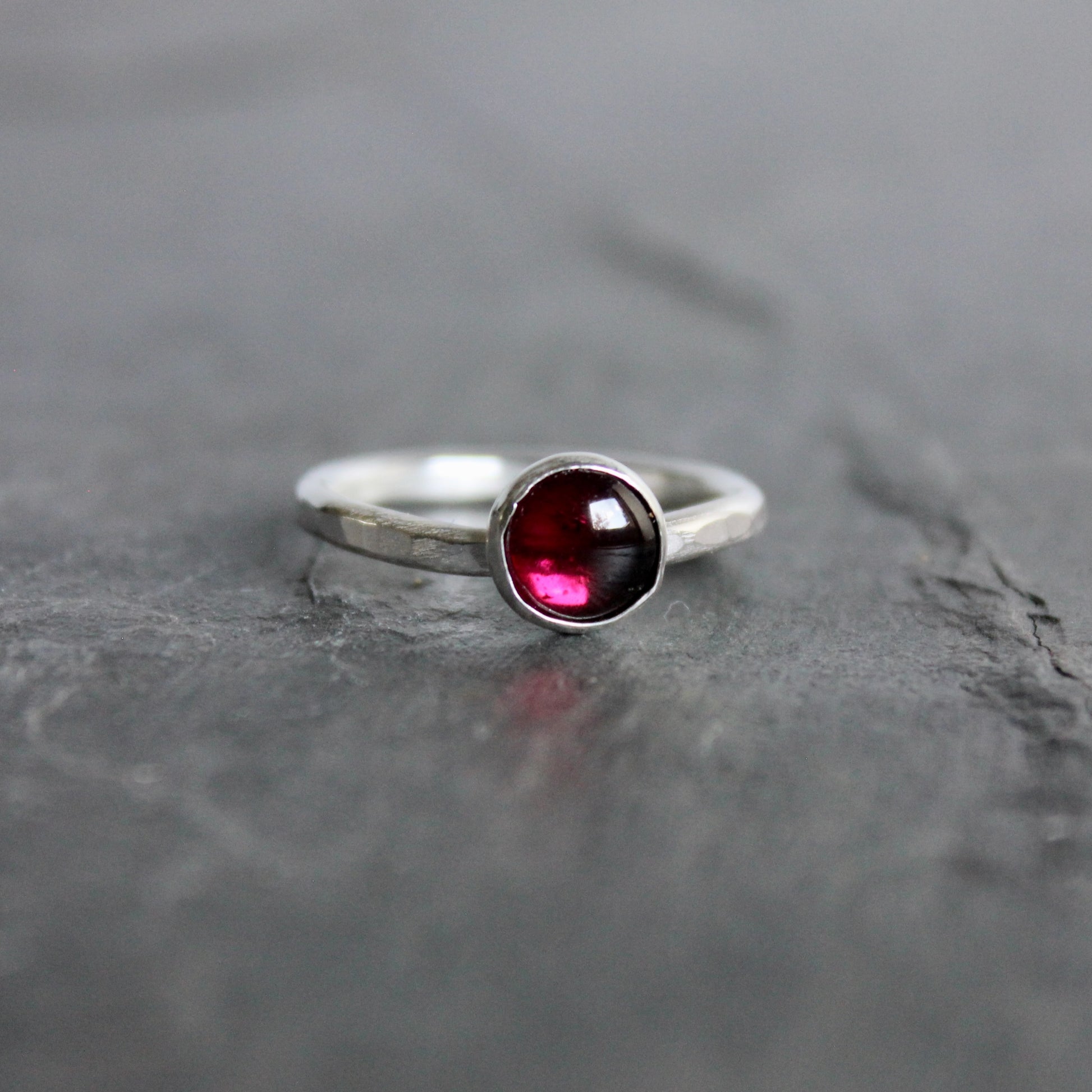 Silver ring with a red gemstone on a gray stone surface