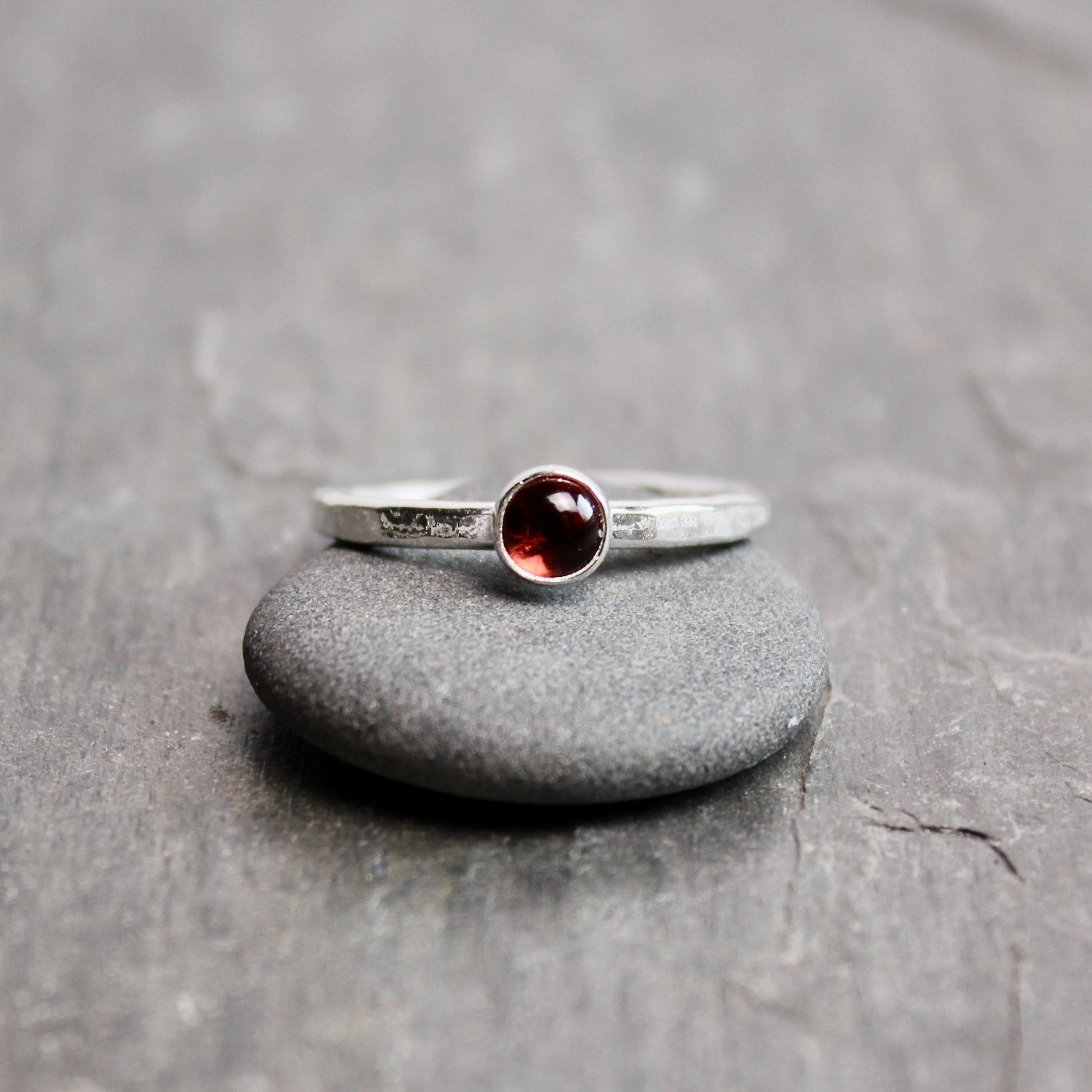 Silver ring with a red gemstone on a gray stone surface