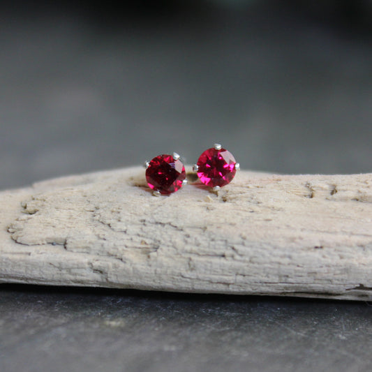 These stud earrings have 4mm round lab created faceted garnets set in sterling silver 4-prong earring settings with ear nuts. 