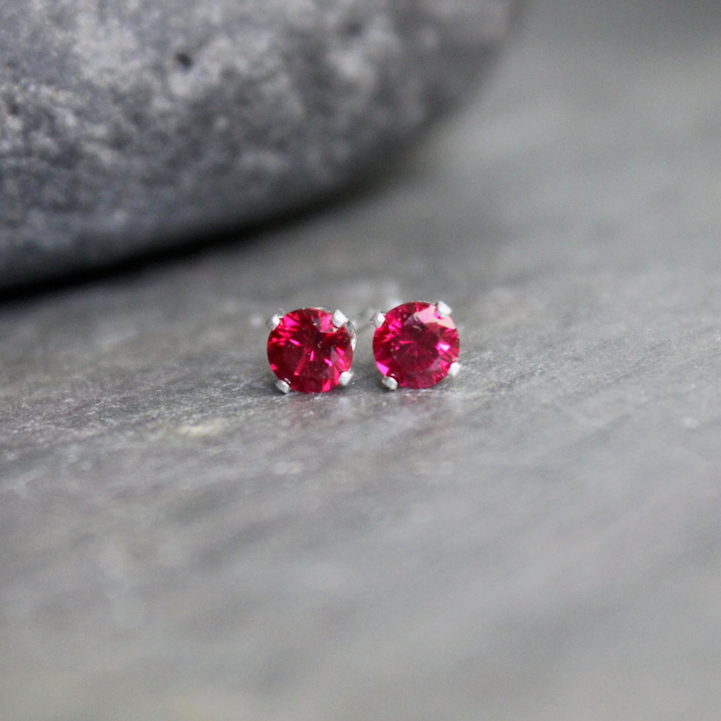 These stud earrings have 4mm round lab created faceted garnets set in sterling silver 4-prong earring settings with ear nuts. 