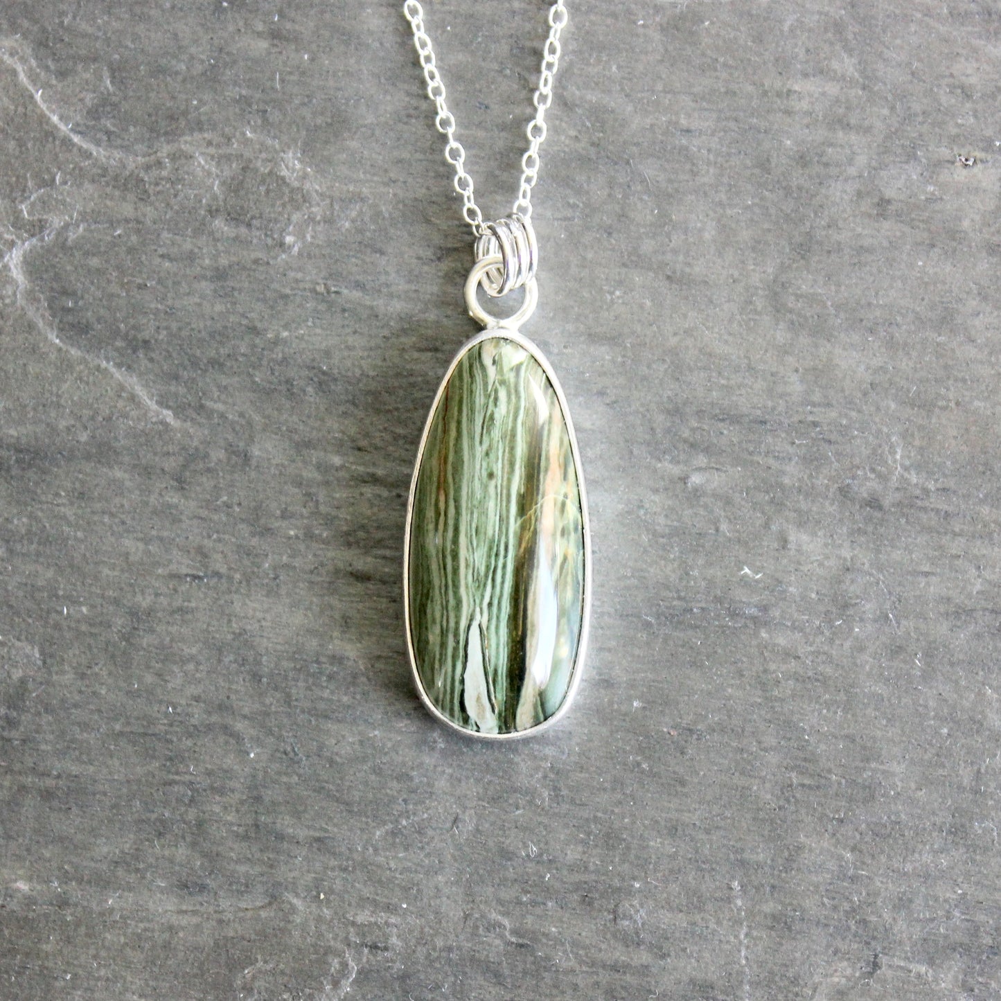 Necklace with a green stone pendant on a gray surface