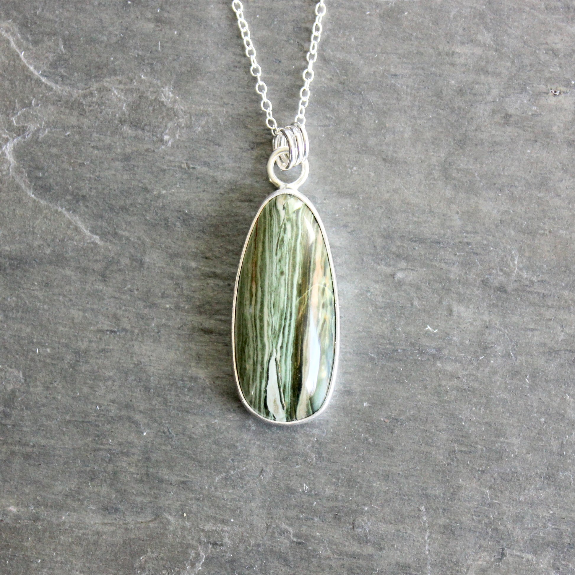 Necklace with a green stone pendant on a gray surface