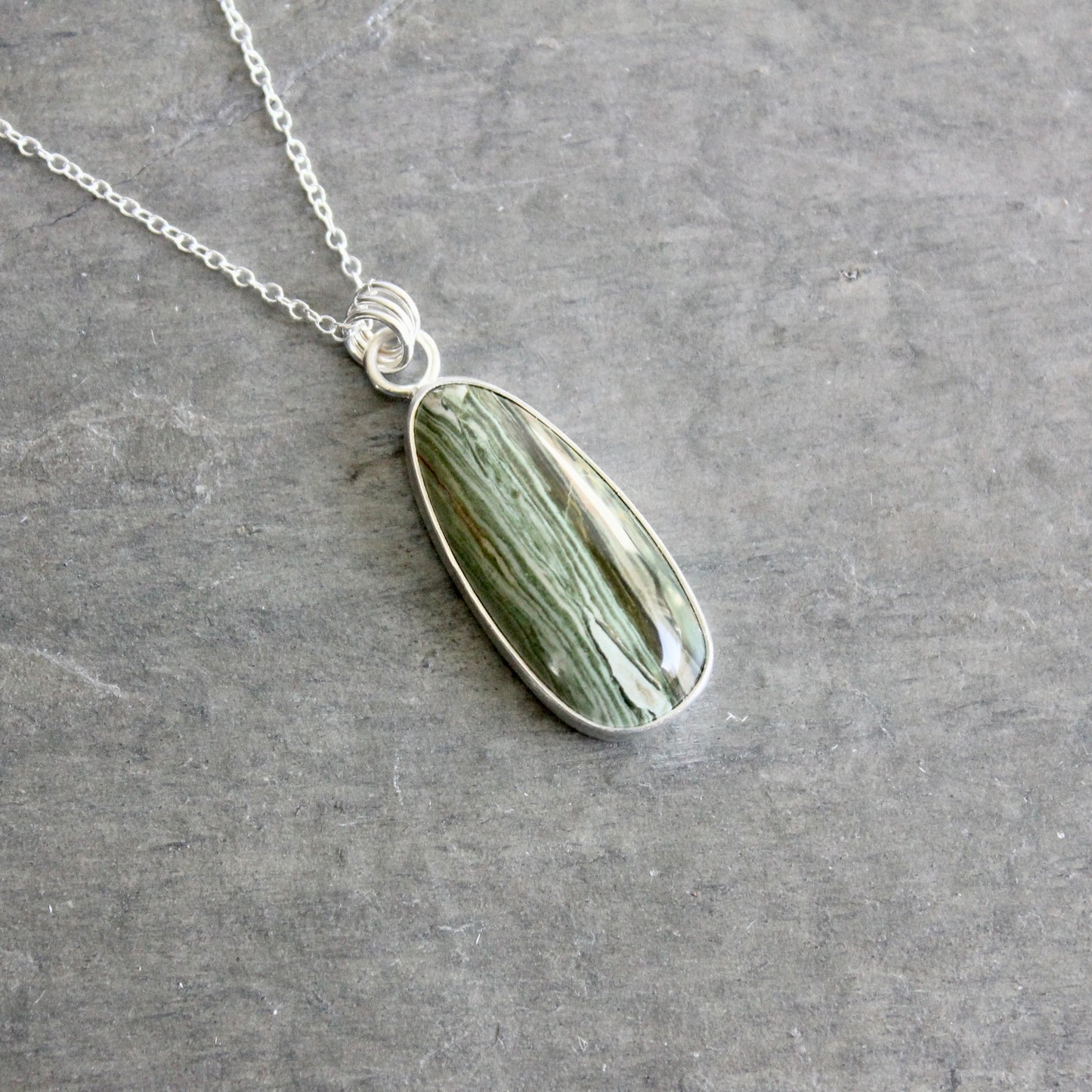 Necklace with a green stone pendant on a gray surface