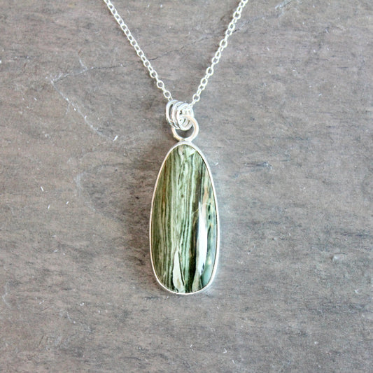 Necklace with a green stone pendant on a gray surface
