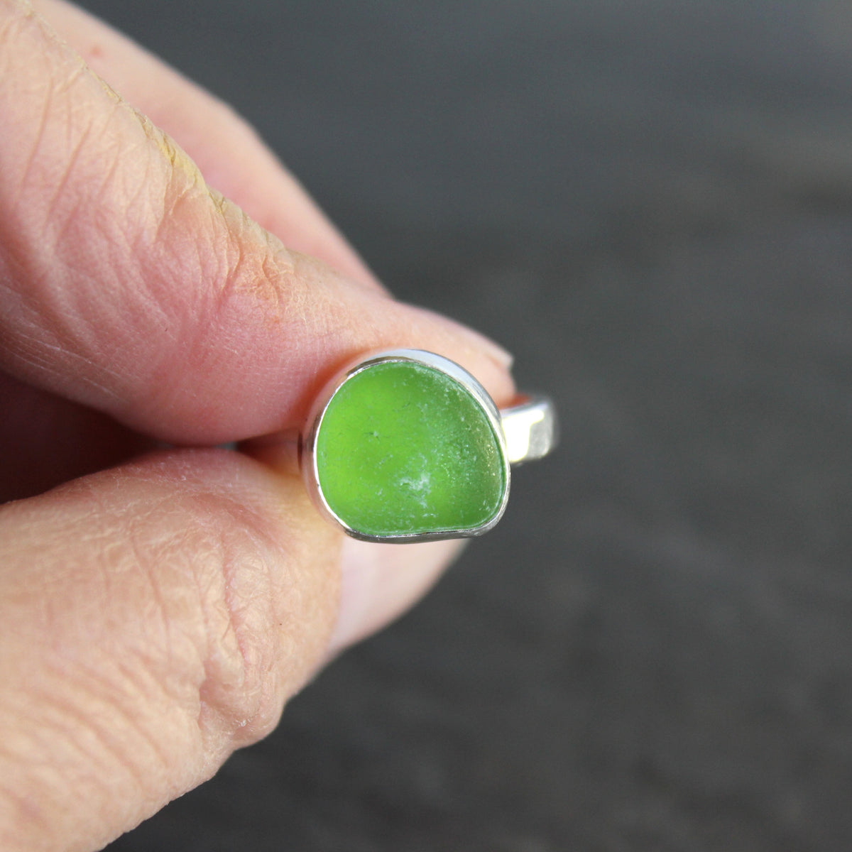 A ring made with a bright green piece of sea glass set in sterling silver. Size 8.5