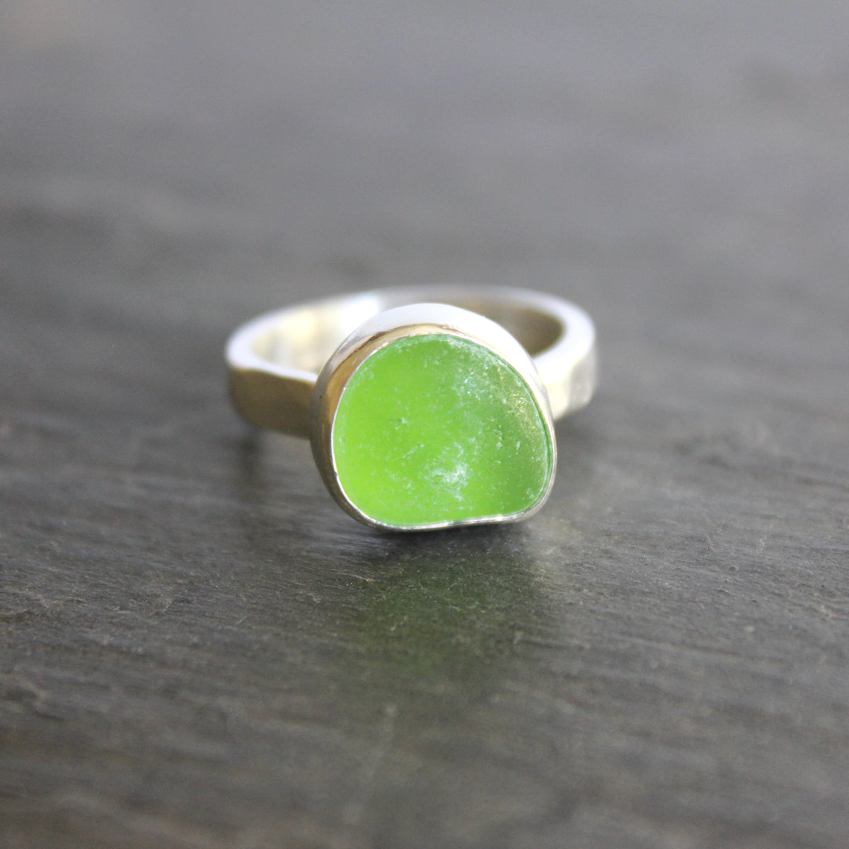 A ring made with a bright green piece of sea glass set in sterling silver. Size 8.5