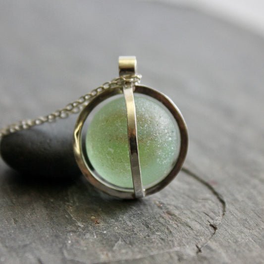 Japanese Codd Bottle Sea Glass in Caged Pendant on stone surface