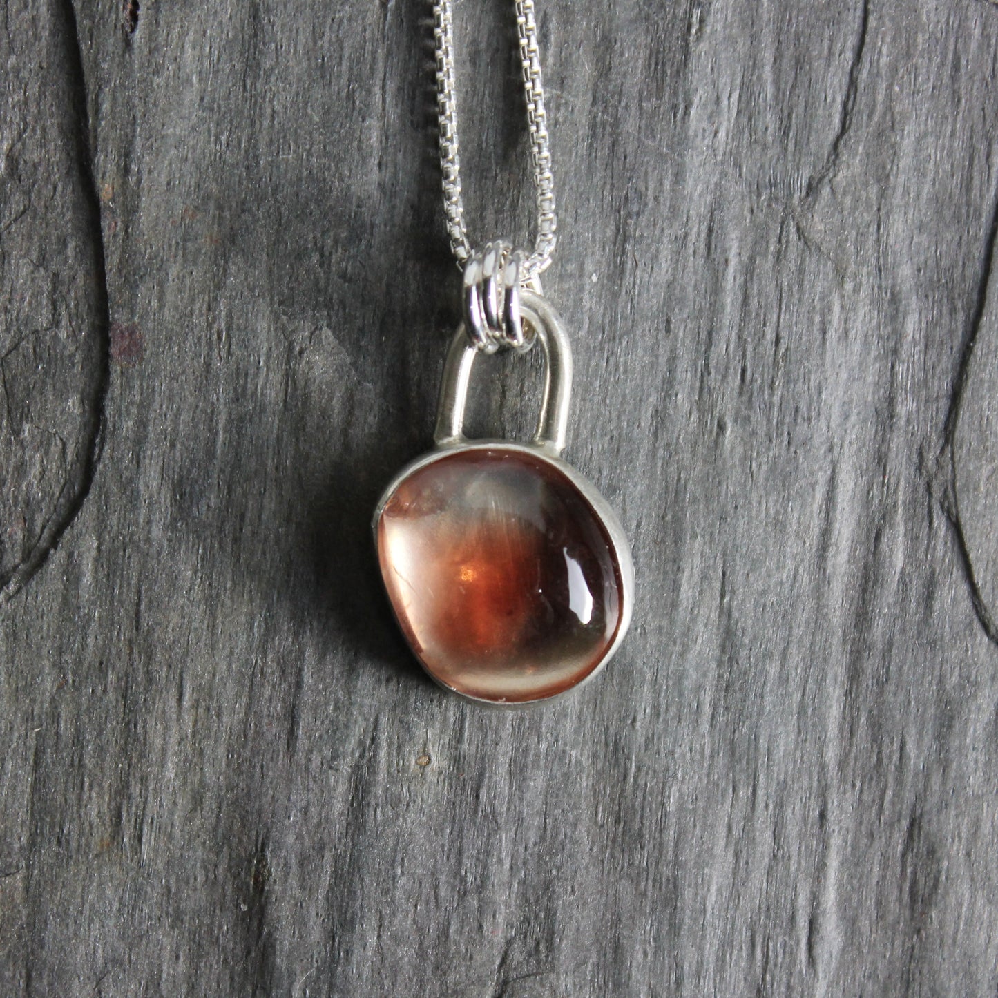Handmade sterling silver red Oregon sunstone cabochon set in a fine and sterling silver bezel setting on a sterling silver chain.