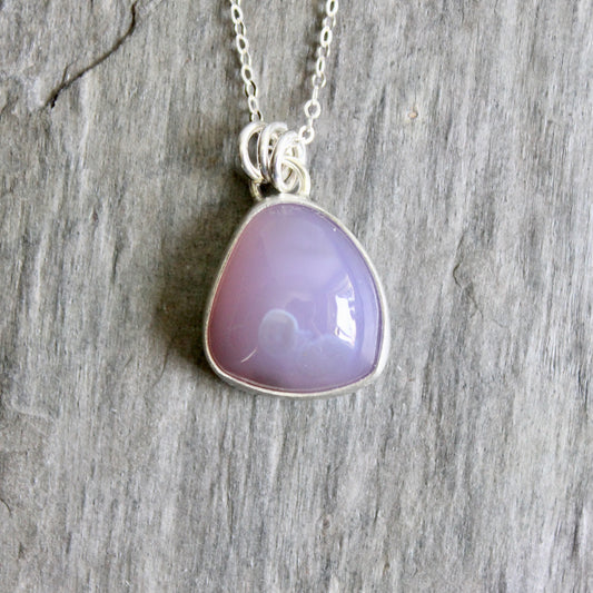 Necklace with a purple teardrop pendant on a wooden surface