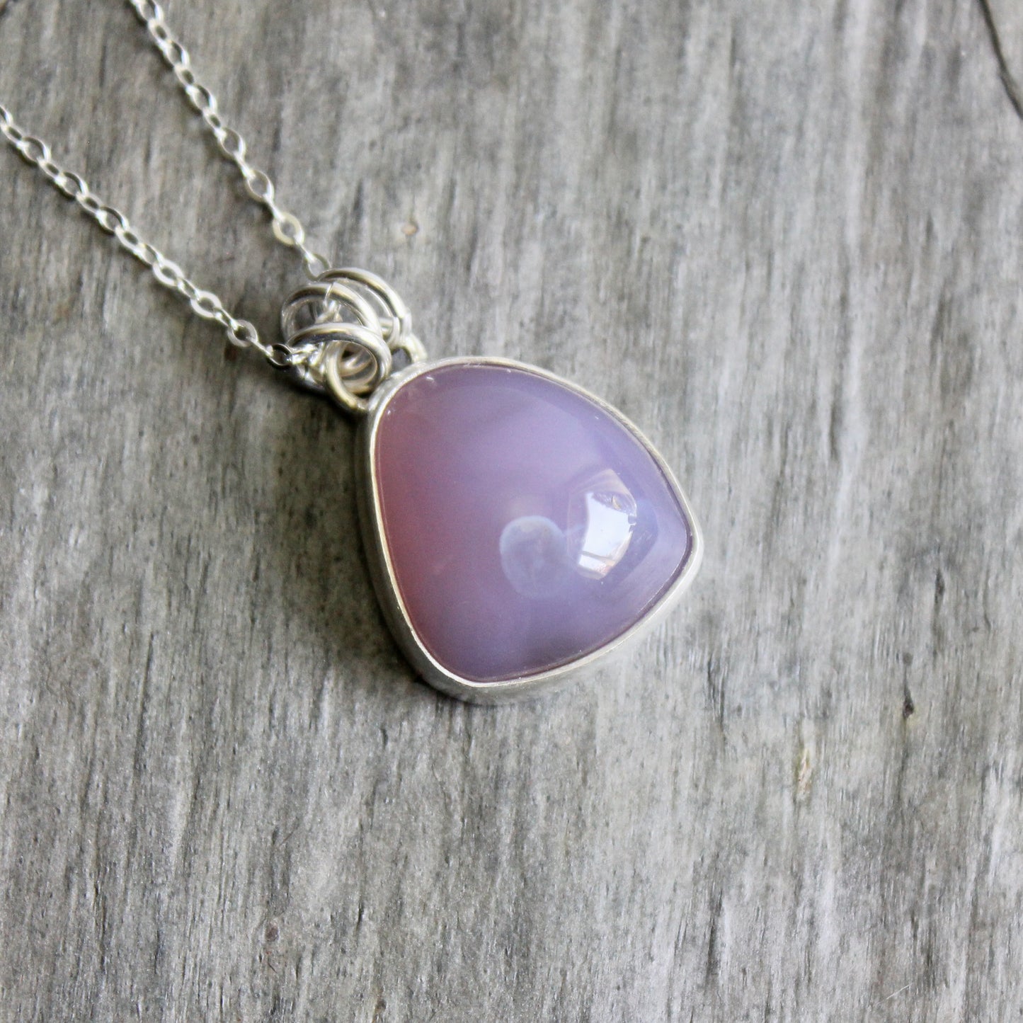 Necklace with a purple pendant on a wooden surface