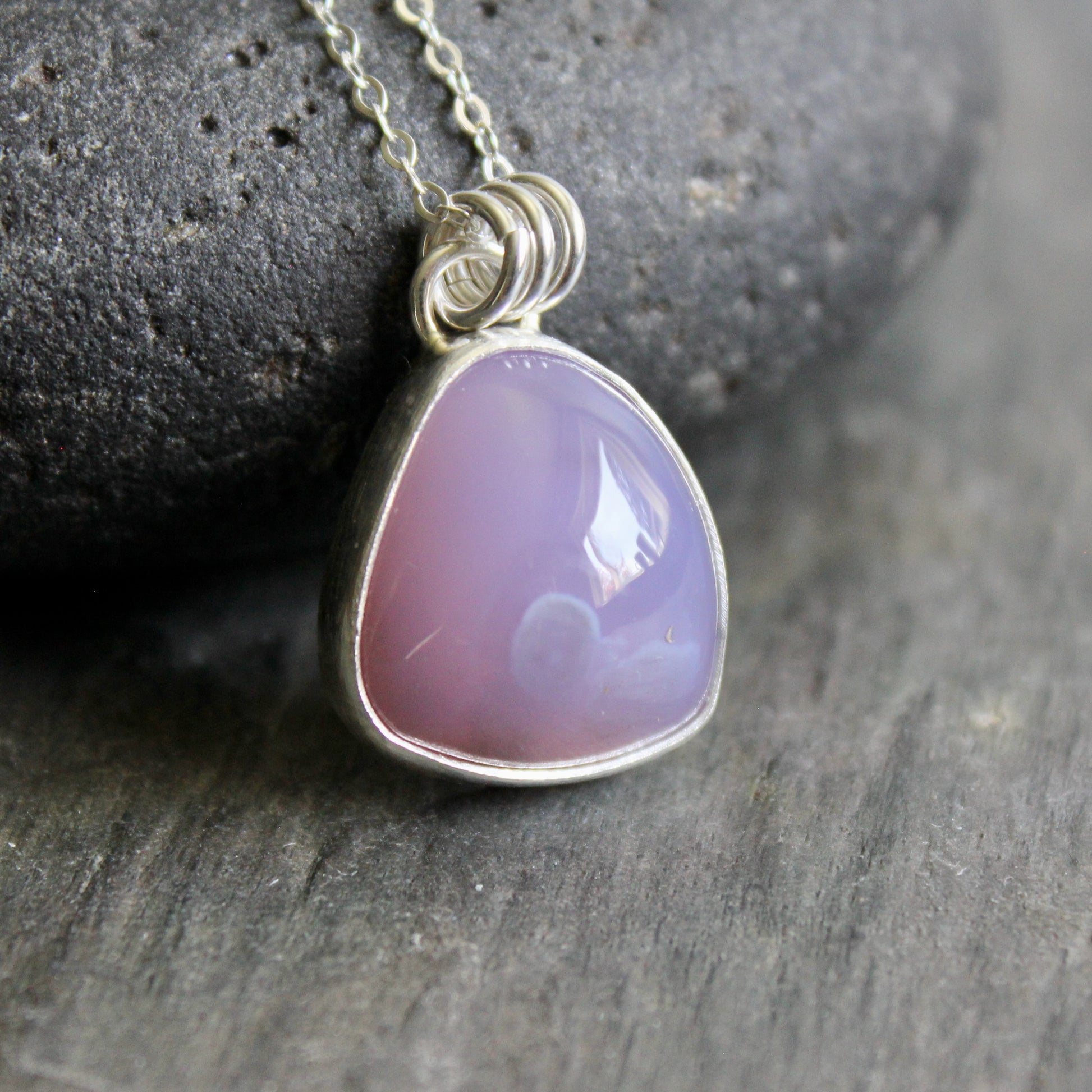 holley blue agate gemstone in a sterling silver setting leaning against a rock.