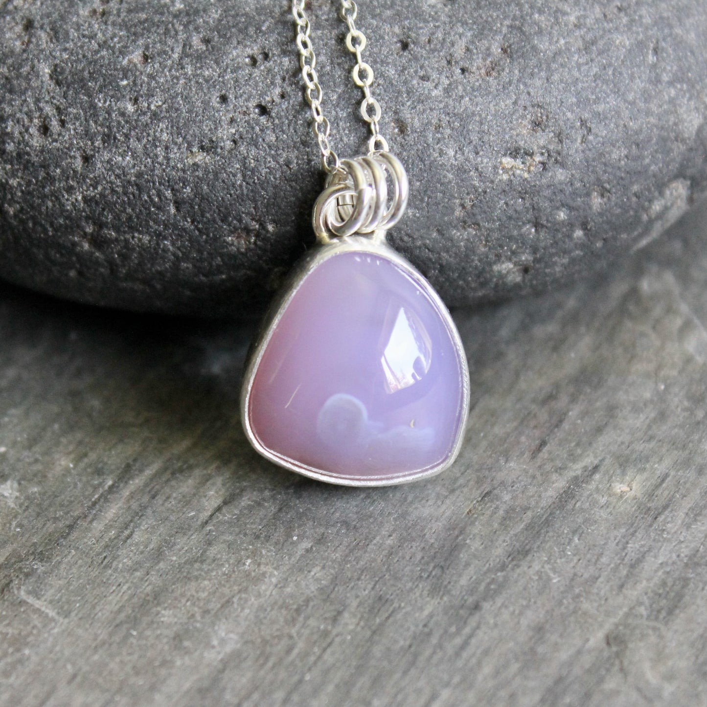 Necklace with a purple pendant on a stone surface