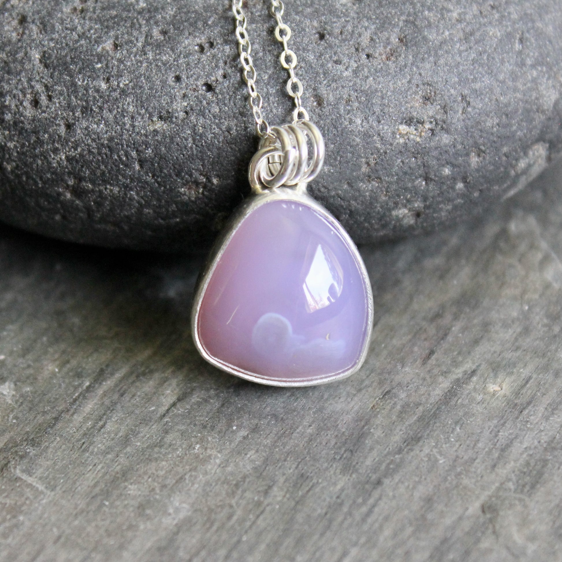 Necklace with a purple pendant on a stone surface