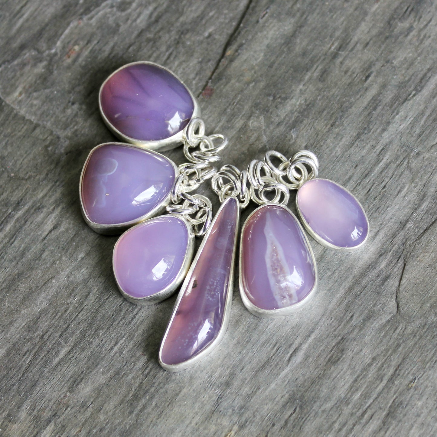 Silver necklace with purple teardrop-shaped pendants on a wooden surface