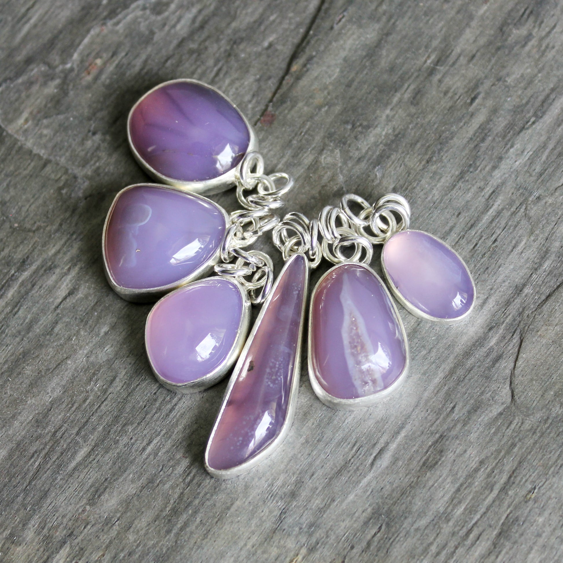 Silver necklace with purple teardrop-shaped pendants on a wooden surface