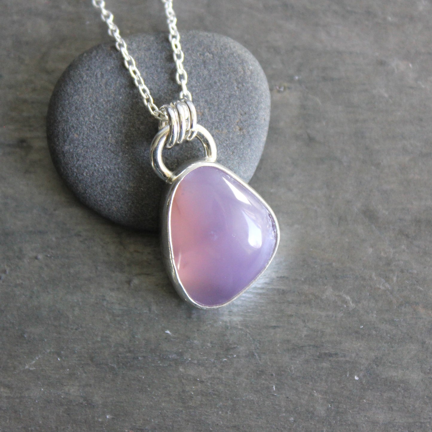 Necklace with a purple holley blue agate pendant on a gray stone surface
