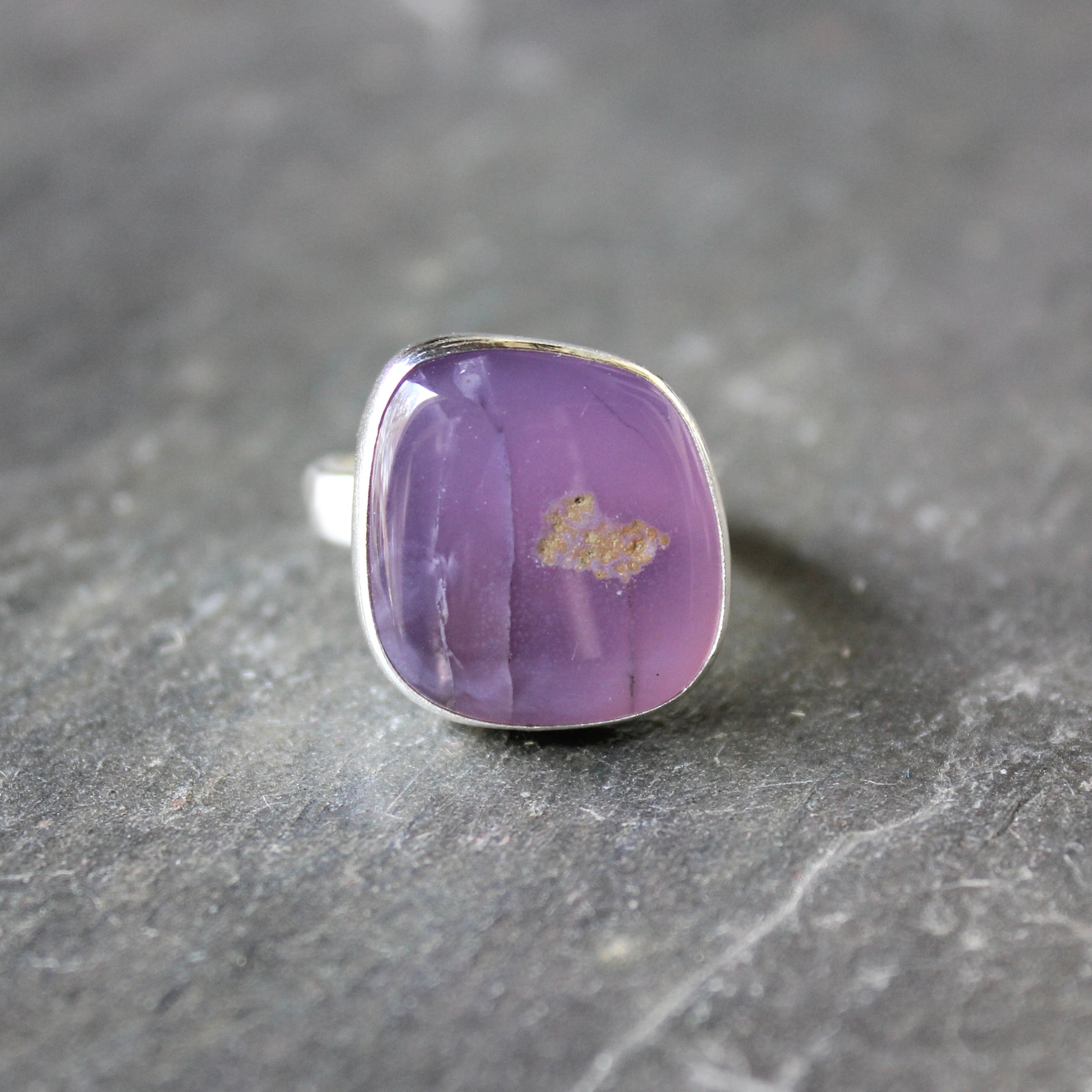 Purple holley blue agate ring with silver setting on a dark gray surface