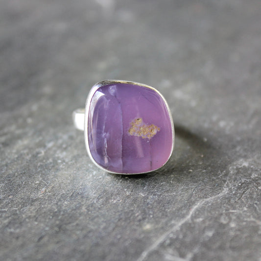 Purple holley blue agate ring with silver setting on a dark gray surface