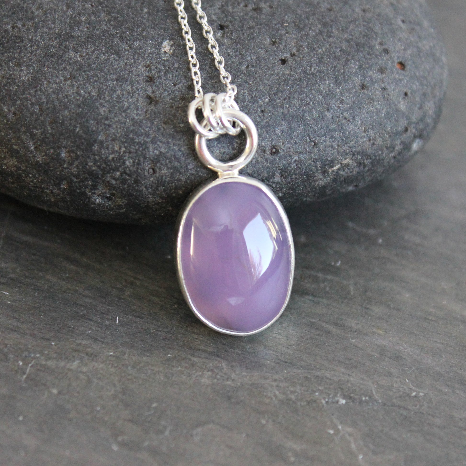 Necklace with a purple holley blue agate pendant on a gray stone surface