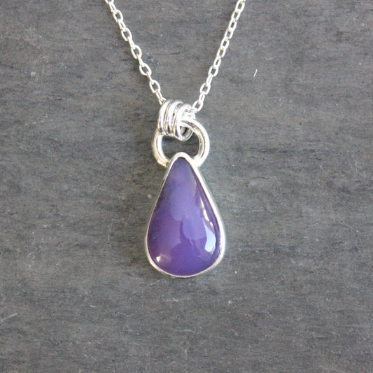 Purple teardrop pendant on a silver chain against a gray background