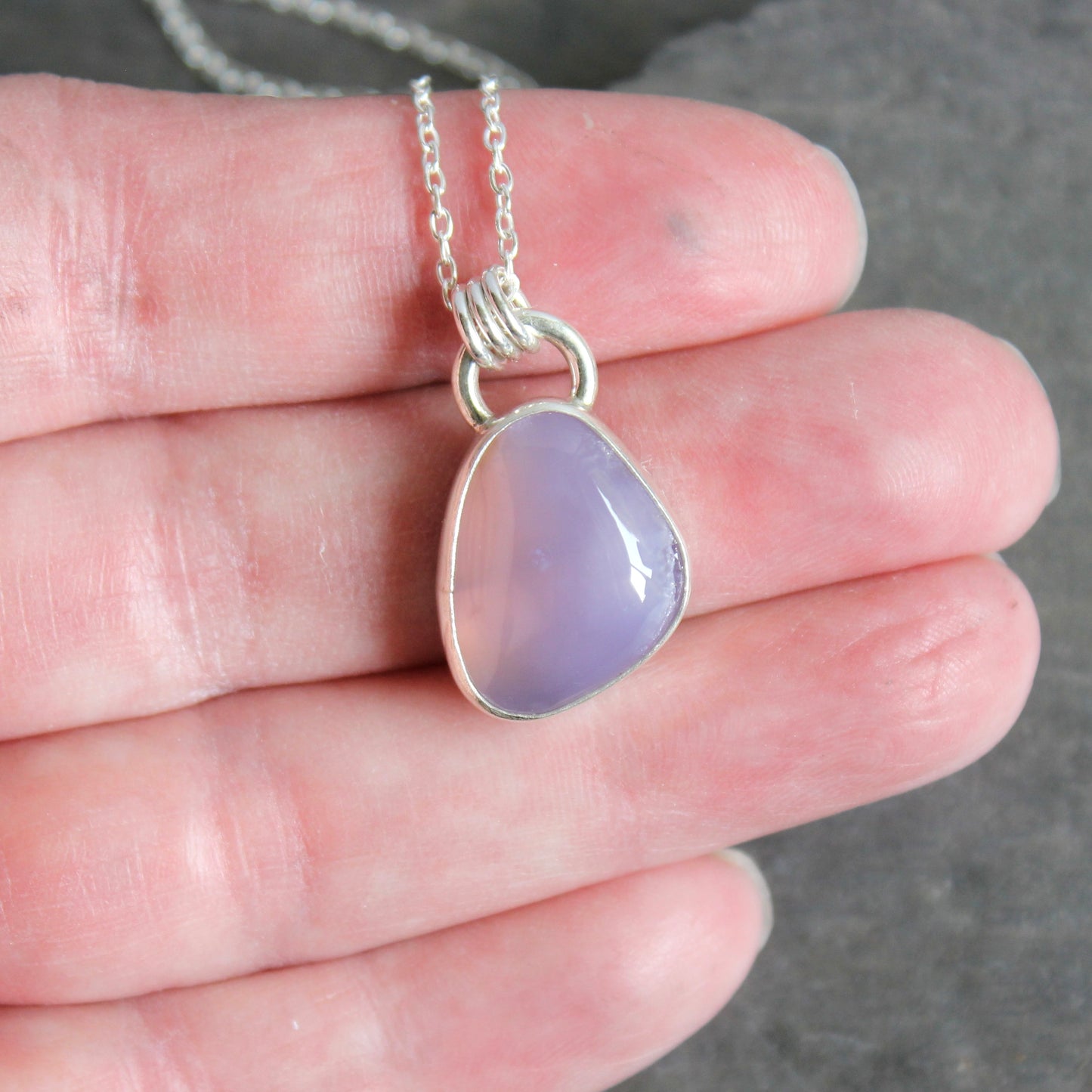 Holley Blue Agate teardrop pendant on a silver chain held between fingers against a neutral background